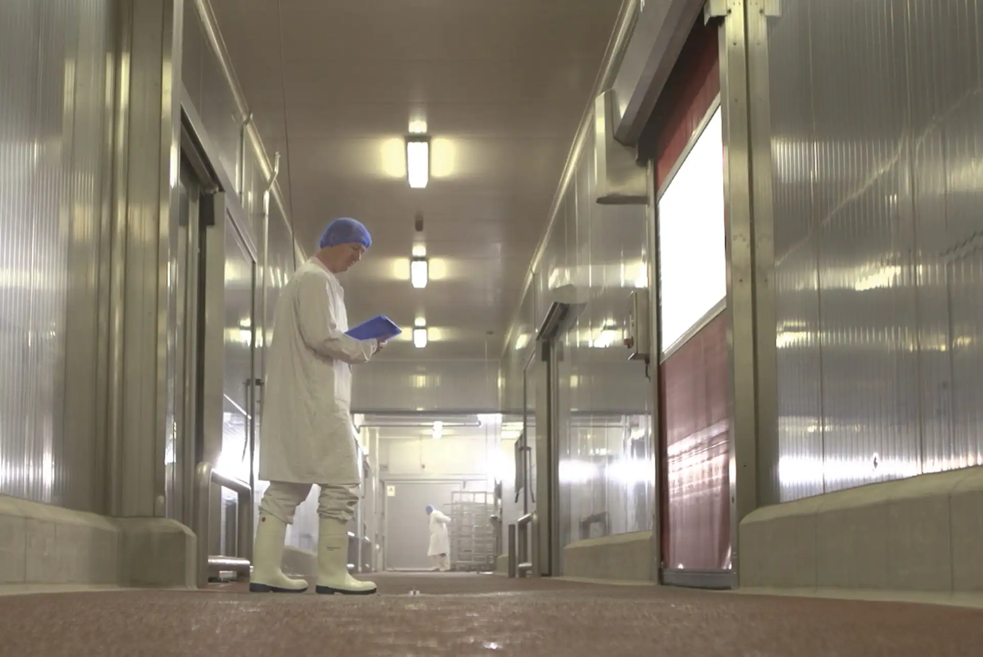 Man walking through hallway in sanitized clothes and rubber boots